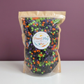 Halloween sensory mix in its original Present Play Co. pouch against a muted plum backdrop with a white tabletop